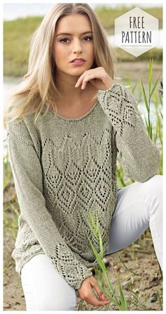 a woman sitting on the ground wearing a green sweater and white pants with her hand under her chin