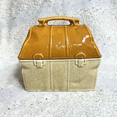 a yellow and white ceramic box with handles