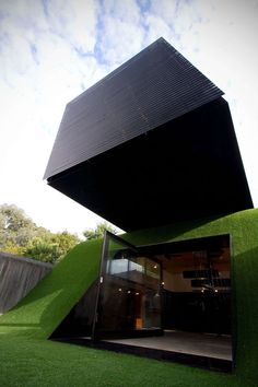 an unusual house with grass on the ground