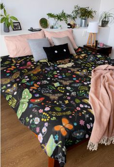 a bed covered in black and pink sheets with lots of flowers on the comforter