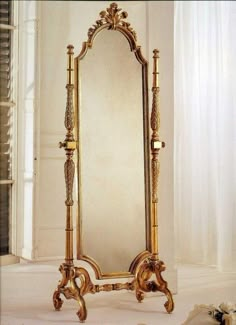 an ornate gold framed mirror sitting on top of a white floor next to a window