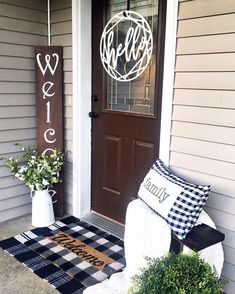 a welcome sign on the front door of a house with potted plants next to it