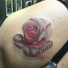 a baseball and rose tattoo on the back of a woman's upper body is shown