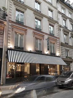 a car is driving down the street in front of a building with awnings