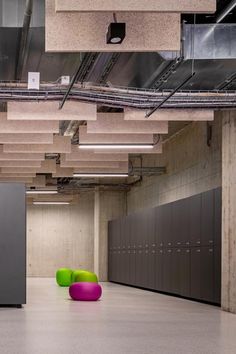 two green and pink chairs sitting in an empty room next to lockers on the wall