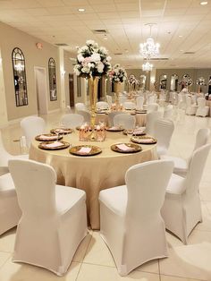 a banquet room set up with white chairs and gold table cloths for formal function