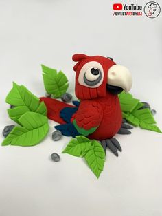 a red bird sitting on top of green leaves and pebbles next to it's eyes