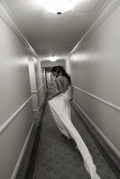 a woman in a long white dress walking down a hallway