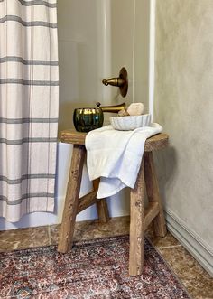 a wooden bench with a towel on it in front of a shower curtain and rug