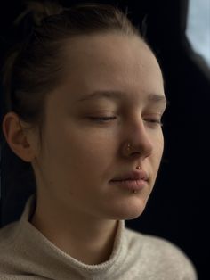 a young woman with her eyes closed and nose piercings in front of her face