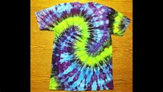 a t - shirt that is sitting on top of a wooden table and has been made to look like a tie dye