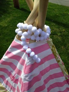 a pink and white umbrella with pom - poms hanging from it's handle