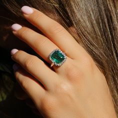 a woman's hand with an emerald and diamond ring