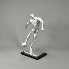 a white paper model of a soccer player on a black base with a gray background