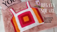 a crocheted bag sitting on top of a pink rug next to a pillow