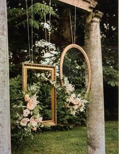 an old photo frame with flowers hanging from it's side in front of a tree