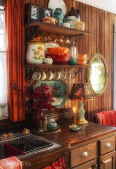 a kitchen with wooden walls and shelves filled with dishes on top of each shelf next to a window