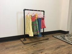 some clothes are hanging on a rack in a room with wood floors and white walls