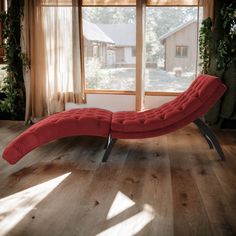 a red chaise lounge chair sitting in front of a window