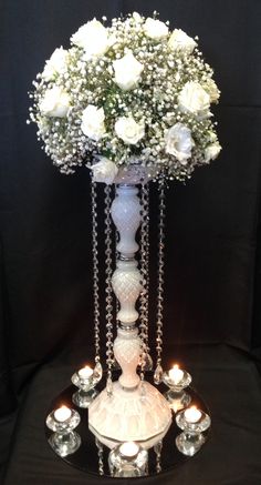 a white vase filled with flowers and candles