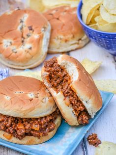 two sloppy joe sandwiches on a blue plate with chips