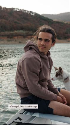 a man sitting on top of a boat next to a dog