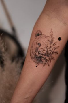 a black and white photo of a bear's head with flowers on its arm