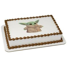 a star wars baby yoda cake on a white plate with brown trimmings