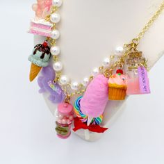 This kawaii statement necklace is called Pink Candy Shop and is a perfect cute charm jewelry gift for any woman in your life including your best friend (or yourself, let's be honest). This piece has been handmade from resin, clay and high quality metal components and features hand painted charms for a quality piece that will be a cute go-to in any charm lovers jewelry collection! Details & Measurements:-Handmade Necklace-High quality glass pearls-Hand-painted charms made from resin & polymer clay-Gumball machine has free floating beads inside! (note it is partially made from glass and fragile)-Choose Gold or Silver Finish -Choose 5, 7 or 9 charms (see list below to find out what charms come on each option)-Charms are chunky and are 1-2" in size (2.5-5cm)-19" (47.5cm) total Necklace Length- Playful Dangle Necklaces With Charms, Playful Dangle Charms Necklace, Playful Dangle Charm Necklace, Fun Charm Necklaces For Gifts, Trendy Handmade Birthday Necklaces, Cute Charm Necklaces For Birthday, Personalized Kawaii Jewelry For Birthday, Kawaii Charms Jewelry For Gift, Kawaii Dangle Earrings For Birthday