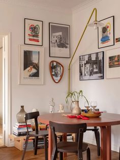 a dining room table with chairs and pictures on the wall above it, along with other decor items