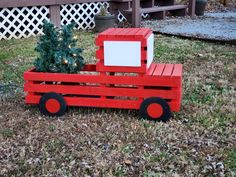 a wooden toy truck with a christmas tree in it's back tire is sitting on the grass