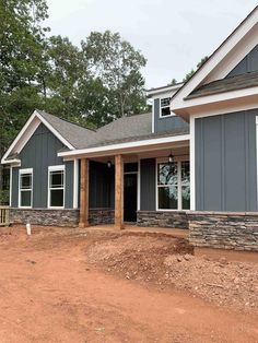 a house is being built in the middle of a dirt lot with trees around it