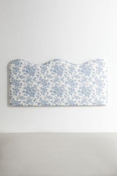 a white and blue floral headboard against a white wall