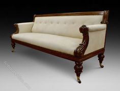 an antique style couch with wood trimmings and white upholstered fabric on the back