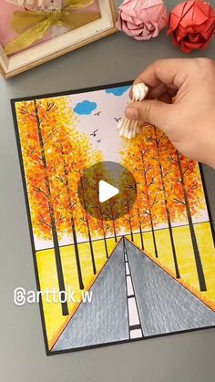 someone is painting an autumn scene on paper