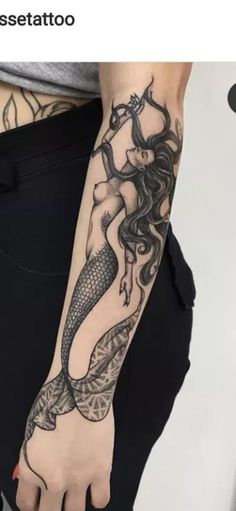 a woman's arm with a mermaid tattoo on it