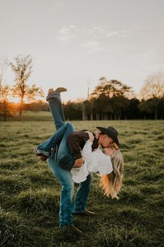 a man and woman kissing in the middle of a field