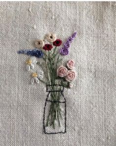 a vase filled with flowers sitting on top of a white cloth covered table next to a wall