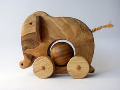 an elephant wooden toy with wheels on a white background and brown rope attached to it