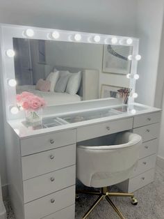 a white vanity with lights on it and a chair