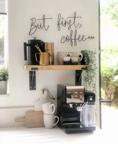 there is a coffee maker and some cups on the shelf