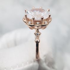 a close up view of a diamond ring on a white cloth with some diamonds around it