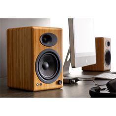 a wooden speaker sitting on top of a desk next to a computer