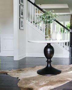 a vase with flowers on top of a table in front of a stair case and railing