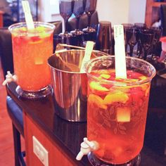 two glasses filled with drinks sitting on top of a counter