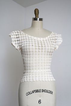 a mannequin wearing a white crochet top