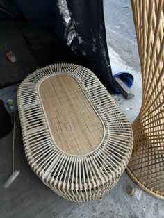 two wicker chairs sitting next to each other on the ground in front of a trash can