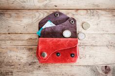 two coin purses sitting on top of a wooden table next to coins and money