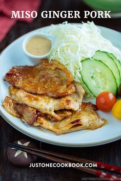 a white plate topped with pancakes and veggies next to dipping sauce on a wooden table