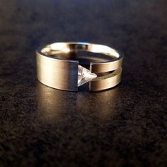 a close up of a ring on a table with a diamond in the middle and an arrow at the top